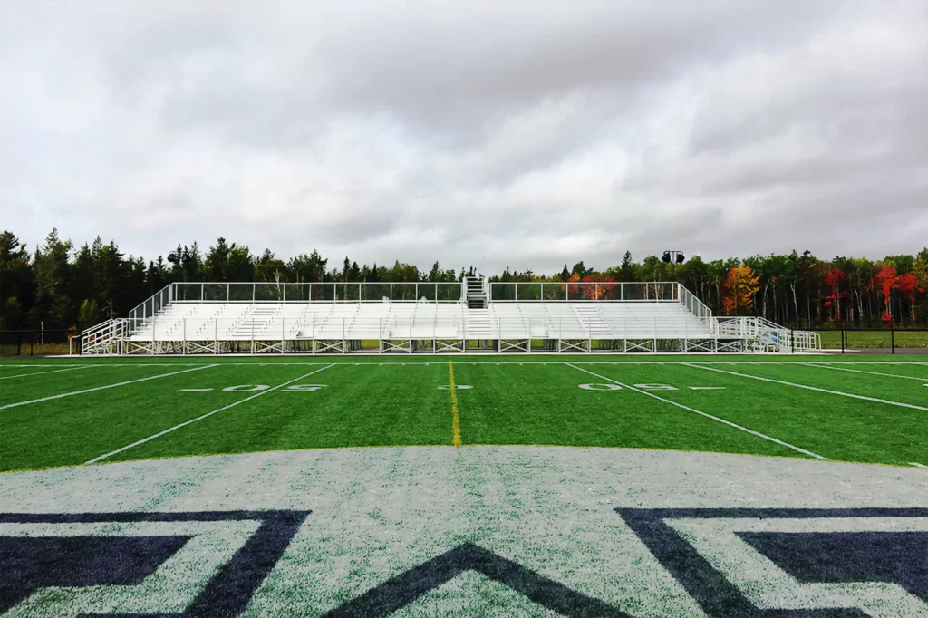 Outdoor elevated bleachers as seen from across an athletic field.