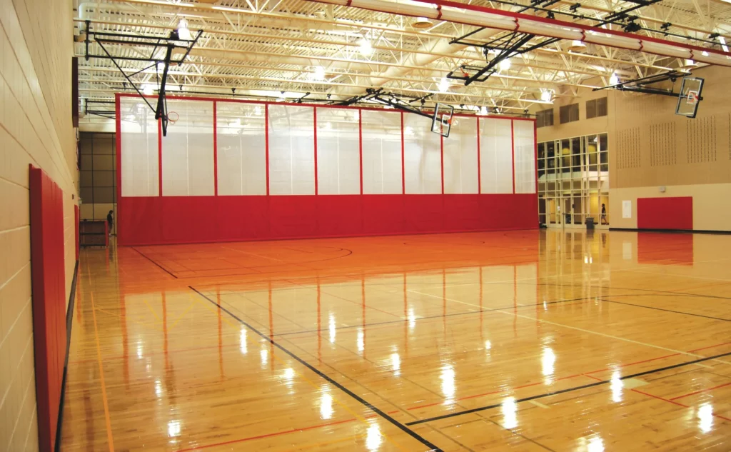 Red and white hanging gym divider on a basketball court.