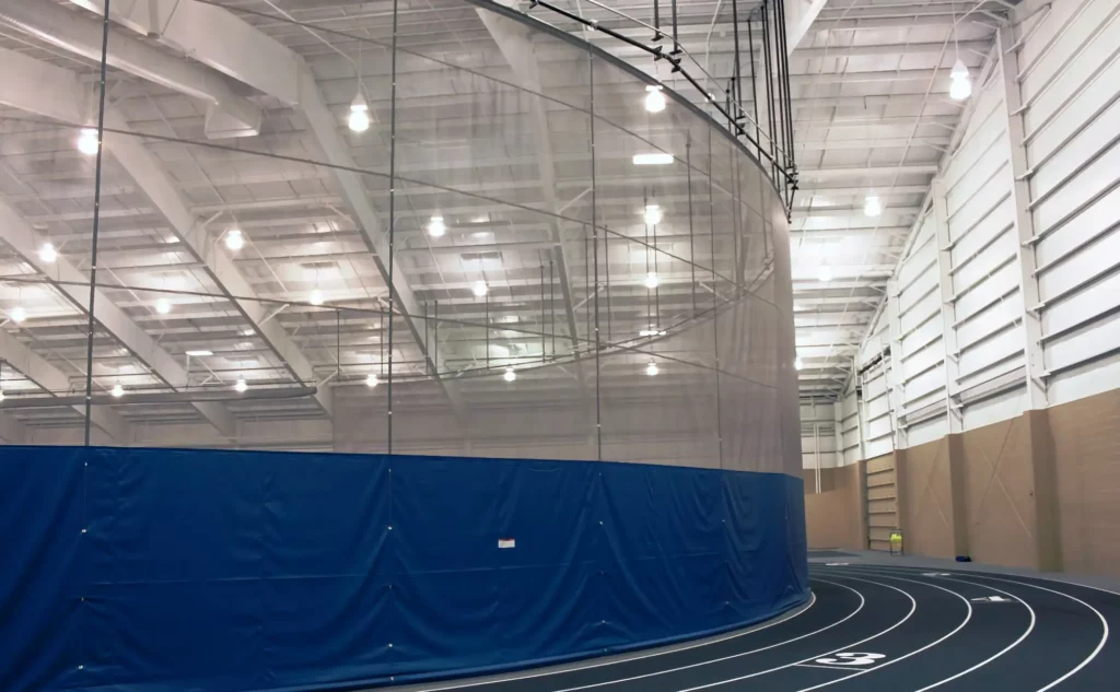 Blue and white gym divider installed around the inner circle to a track to shields runner on the track.