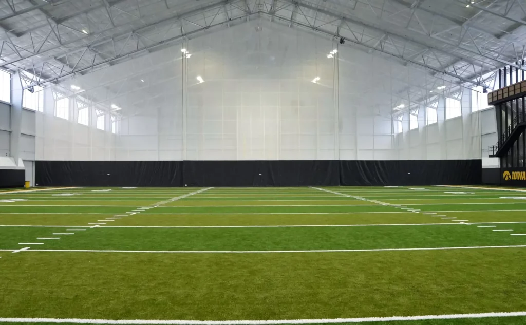 Black and white handing gym divider separates green astro-turf areas.