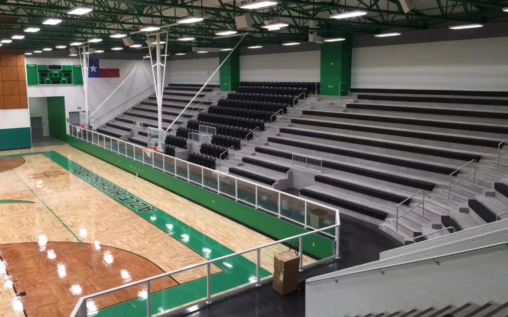 Indoor bleachers surround a basketball court.