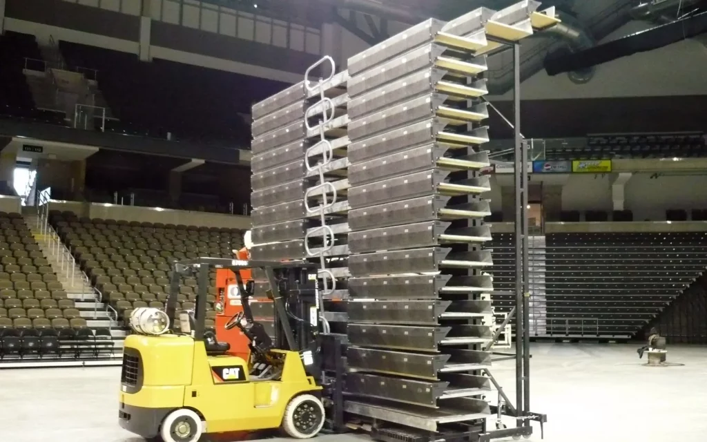 Indoor, portable bleachers are moved by a forklift.