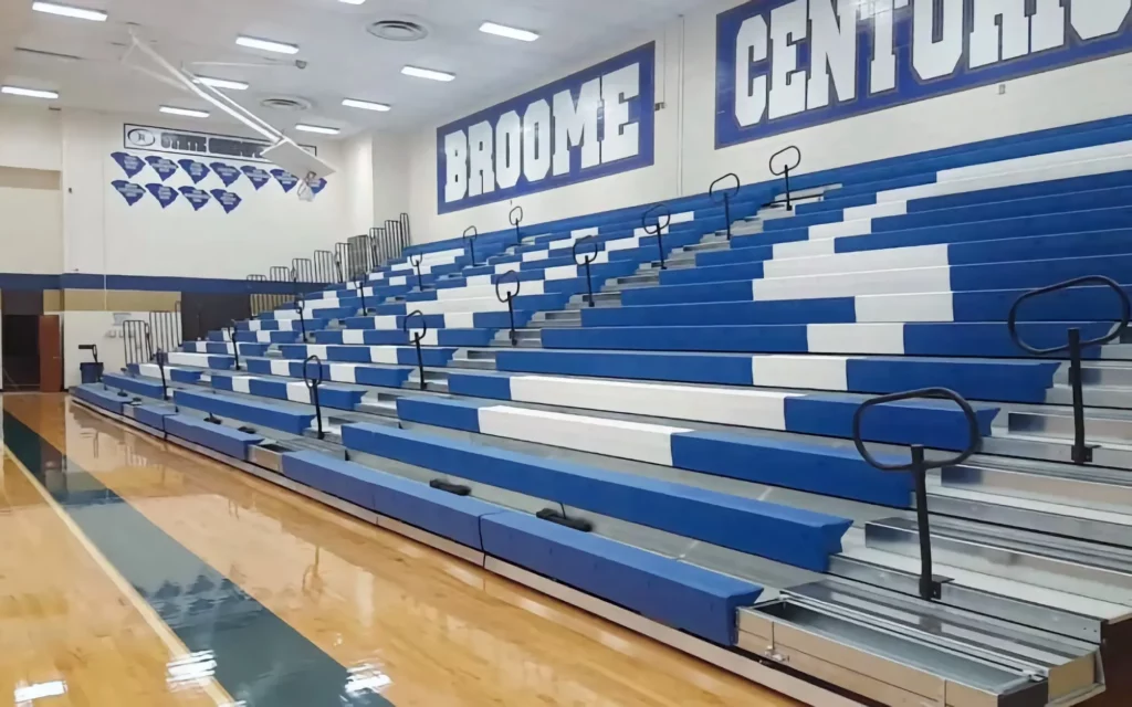 Blue and white indoor telescopic bleachers are expanded in a gym.
